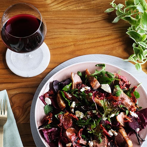 Glass of pinot noir and a bowl of roast duck salad
