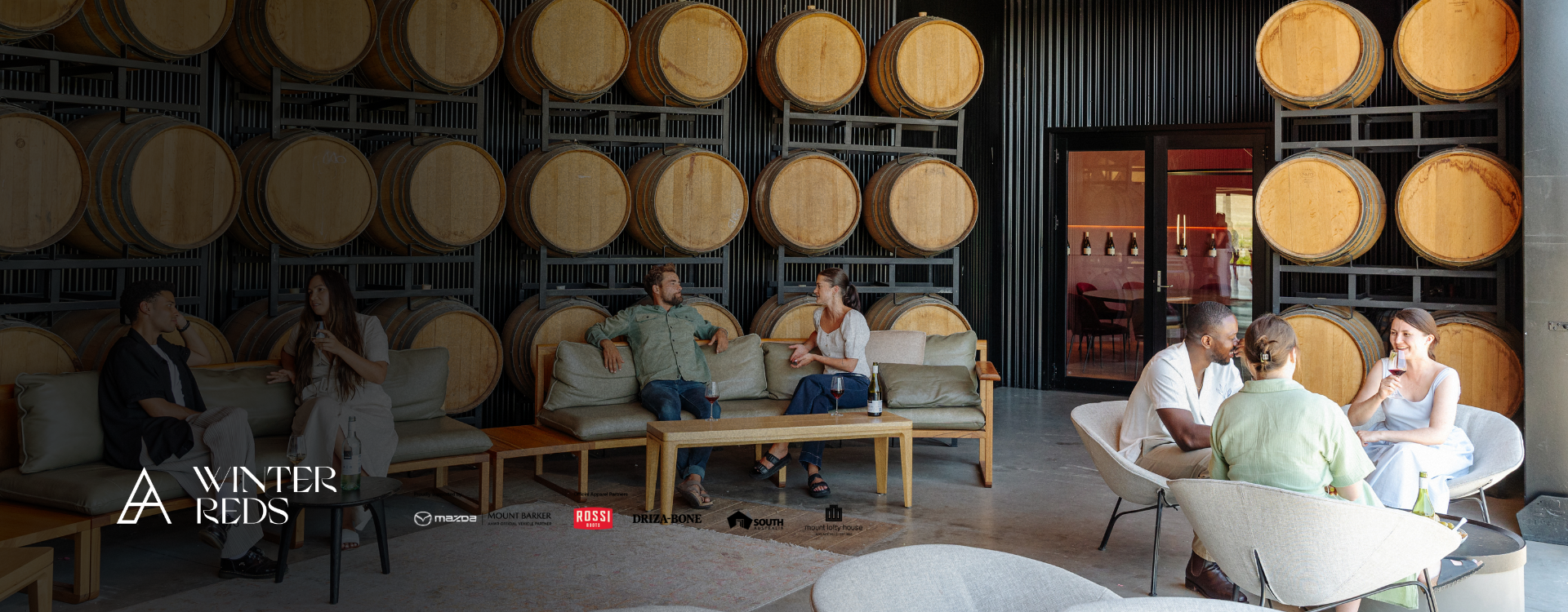 Group of people sat enjoying wine in nepenthe Cellar Door Barrel Room.