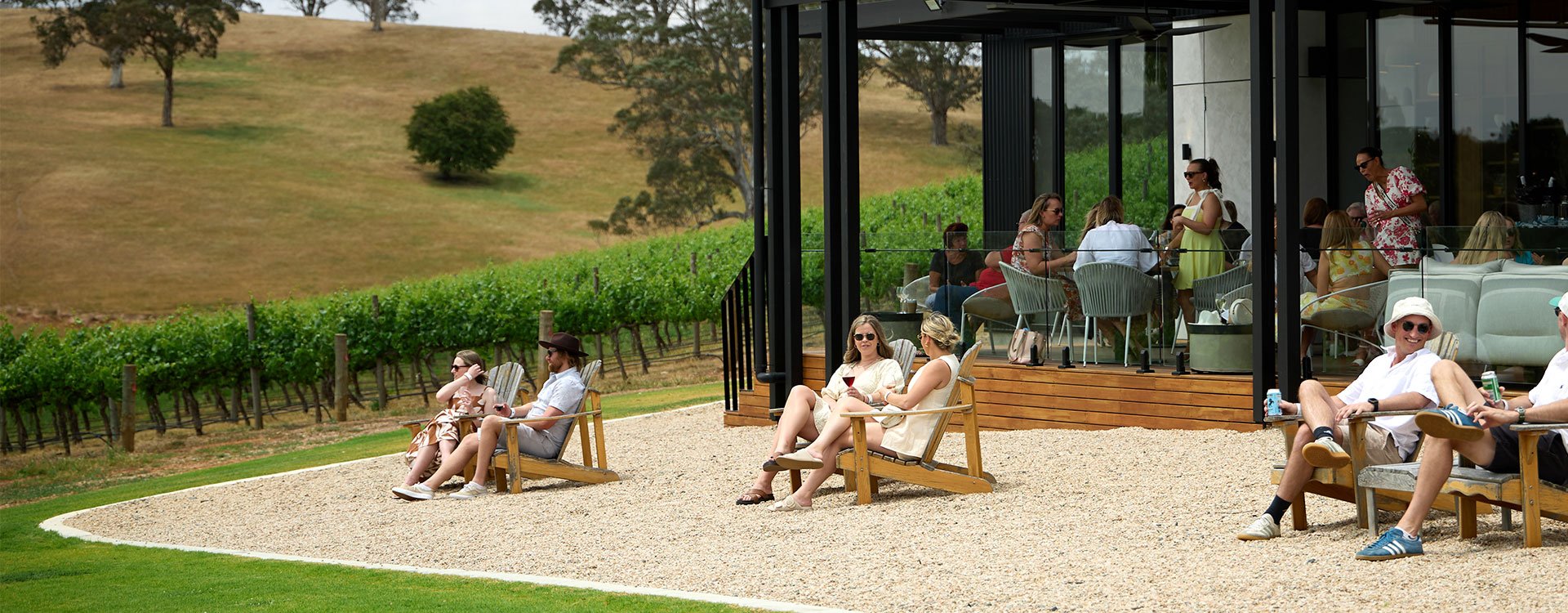 a group of people smiling and sat on outdoor furniture on the lawn at nepenthe Cellar Door.