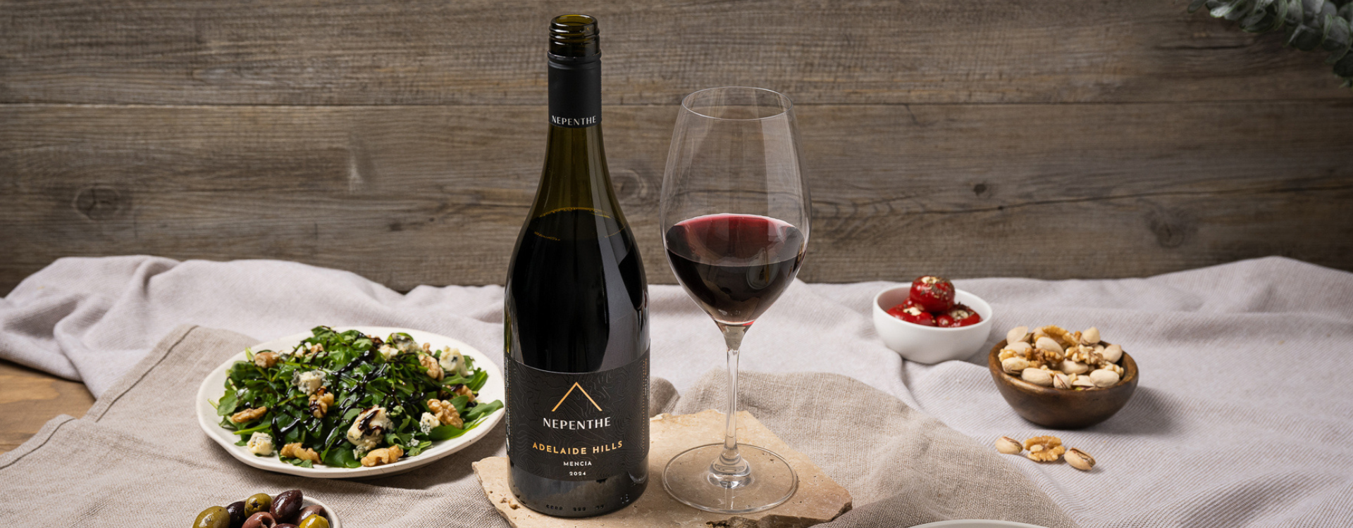 Nepenthe Pinnacle Red wine bottle with a glass poured on a table full of colourful food