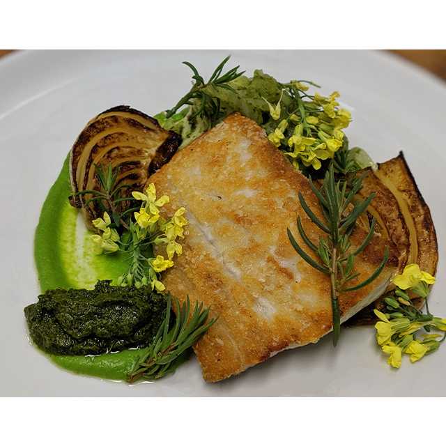 Seared Kingfish dish with various vegetables, sauce and garnishes