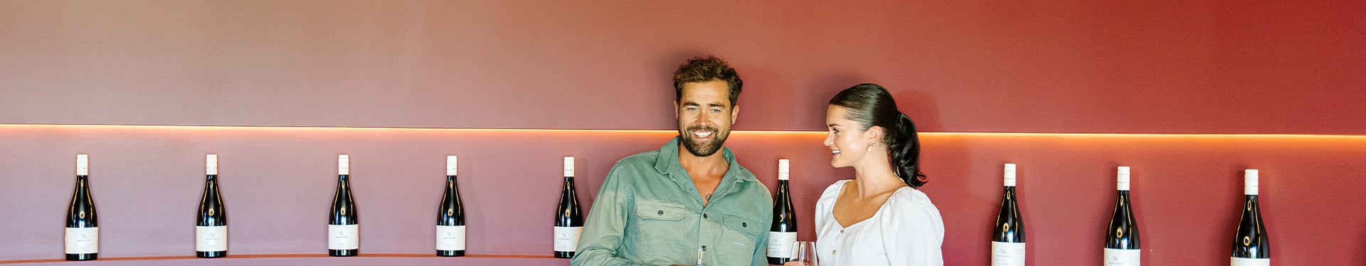 Two people with a red backdrop that has wine in it